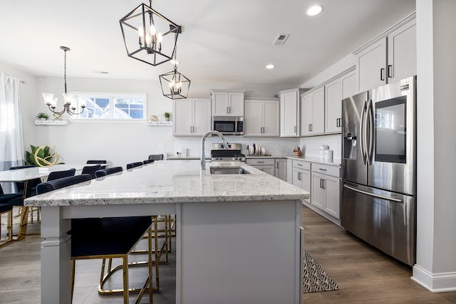 a kitchen with grey cabinets white counters and stainless steal appliances copy